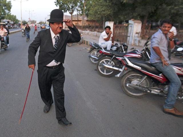 Ashok Aswani dresses up as Charlie Chaplin and gestures at people as he walks on a road in Adipur in Gujarat. (Reuters/Danish Siddiqui)