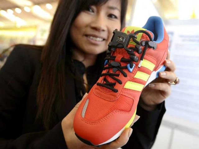 A woman shows a South Korean invention to tie shoes with a single touch, shaped with a hook and a stop loop to control the tightness. AFP/Fabrice Coffrini