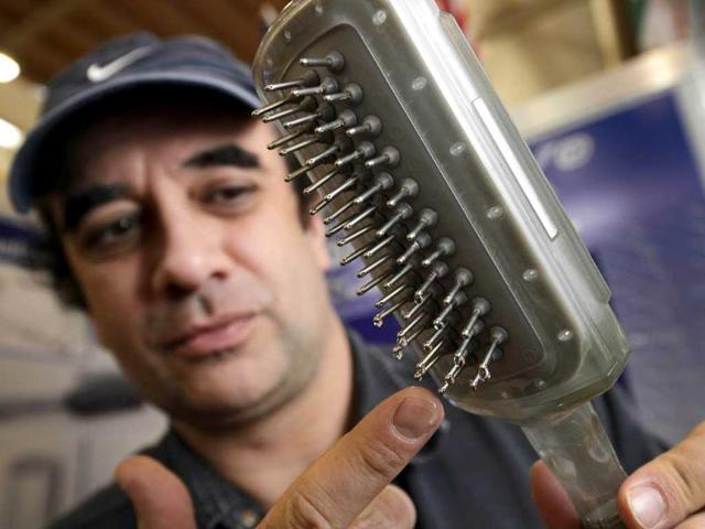 Andre Piatetsky from the US presents his invention, a treatment hairbrush fitted with a liquid-reservoir that disperses treatment solution over the user's scalp during hair brushing. AFP/Fabrice Coffrini