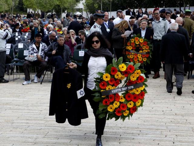 The daughter of Polish-born Israeli Holocaust survivor Mordechai Fuchs, who passed away three months ago, holds his jacket which bears a Star of David and the word "Jude", written on it during the annual Holocaust Memorial Day ceremony at the Yad Vashem Holocaust Museum in Jerusalem. AFP Photo/Gali Tibbon