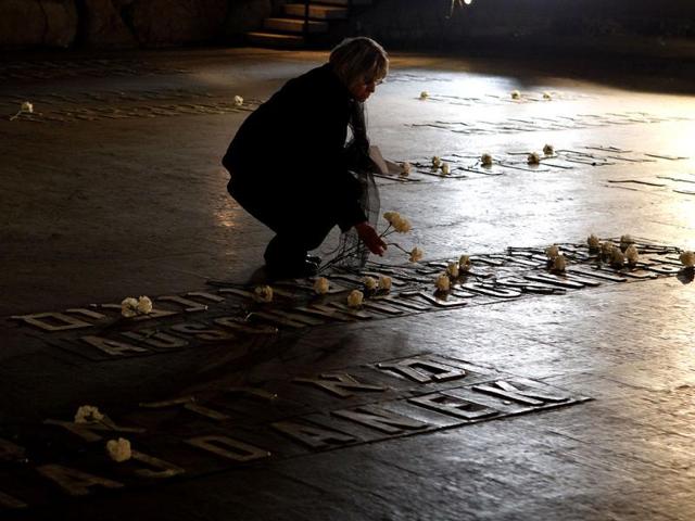 A woman places a flower at the Hall of Remembrance where the names of major killing sites of Jews are written during a Holocaust Remembrance Day ceremony at the Yad Vashem Holocaust Museum in Jerusalem. AFP Photo/Gali Tibbon