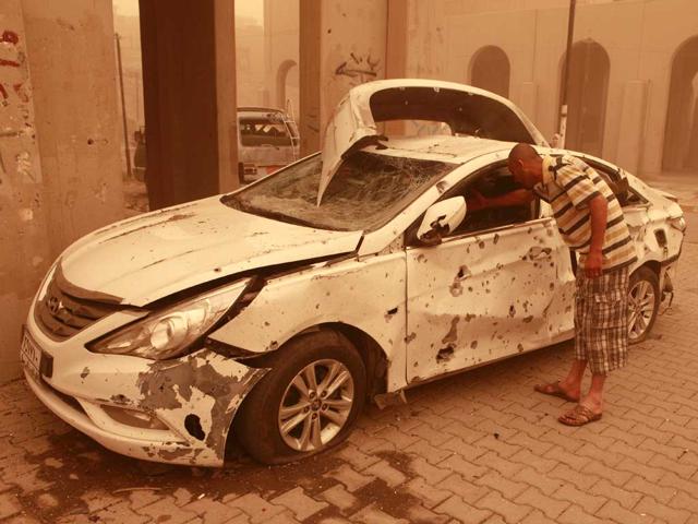 Mahmoud Ali inspects his destroyed car during a sandstorm after a car bomb explosion in Haifa Street, Baghdad, Iraq. A wave of morning bombings across several cities on Thursday, killing and injuring dozens of Iraqis, police said, shattering weeks of calm in a reminder of the nation's continued insurgency. (AP Photo/Karim Kadim)
