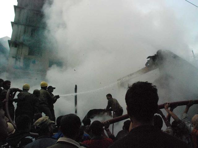 Fire fighters try and douse out a fire at the the main market square of Darjeeling town. HT Photo/Amitava Banerjee