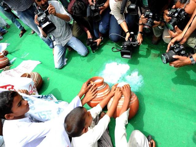 Milkmen from Delhi and Western Uttar Pradesh are watched by media representatives as they pour milk into a drain during a protest in New Delhi. (AFP photo/Prakash Singh)