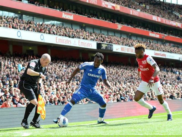 The assistant referee watches the position of the ball as Chelsea's Ghanaian midfielder Michael Essien (2nd L) vies with Arsenal's Cameroonian midfielder Alex Song (R) during the English Premier League football match between Arsenal and Chelsea at The Emirates Stadium in north London. (AFP Photo/Adrian Dennis)