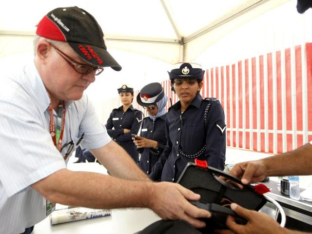 Bahraini policemen check a reporter's bag at the entrance gate prior to the start of the Bahrain Formula One Grand Prix at the Formula One Bahrain International Circuit in Sakhir, Bahrain. (AP Photo/Luca Bruno)