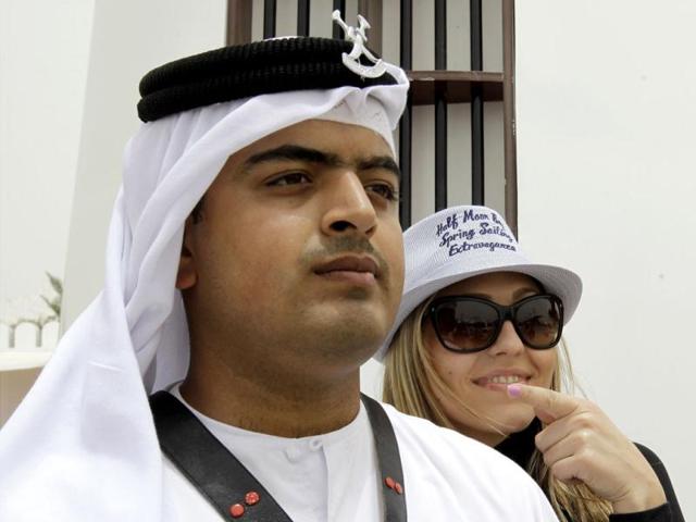 A F1 fan poses for picture with a Bahraini policeman wearing traditional uniform ahead of the Formula One Grand Prix at the Bahrain International Circuit in Sakhir, Bahrain. (AP Photo/Hassan Ammar)
