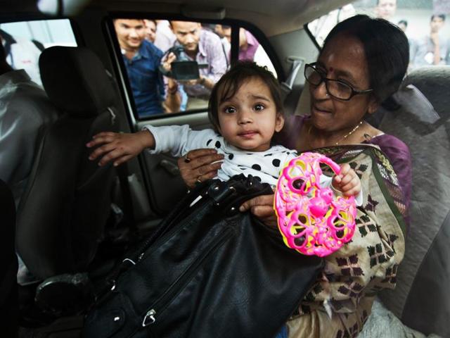 One year old Aishwarya Bhattacharya is held by her grandmother in a car at IGI airport in New Delhi, shortly after her arrival. AFP/Prakash Singh