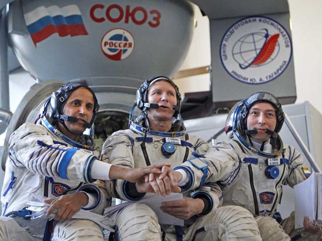 Members of the next expedition to the International Space Station, US astronaut Joseph Acaba, left, and Russian cosmonauts Genady Padalka, center, and Sergey Revin, right, shake hands before their final preflight practical examination in a mock-up of a Soyuz TMA space craft at Russian Space Training Center in Star City outside Moscow, Russia.(AP Photo/Mikhail Metzel)
