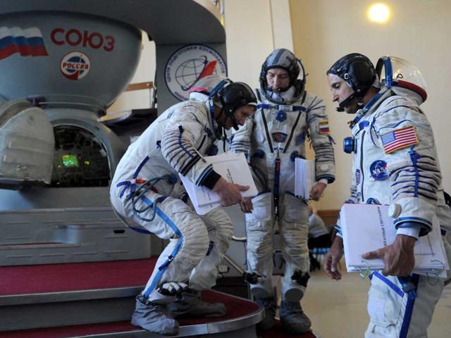 Crew members of the next expedition to the International Space Station (ISS), US astronaut Joseph Acaba (R) with Russian cosmonauts, Gennady Padalka (L) and Sergei Revin (C), confer in front of a mock-up of a Soyuz TMA space craft during their final preflight practical examination at the Cosmonaut Training Centre in Star City, outside Moscow. AFP/ Kirill Kudryavtsev