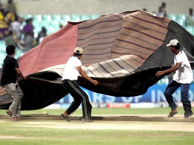 Groundmen cover the ground due to incessant rain, just before the start of an IPL-5 match between KKR and Deccan Chargers in Kolkata. (PTI PhotoAshok Bhaumik)