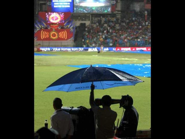 Groundsmen cover the ground with tarpaulin as it rains before the start of the match between Royal Challengers Bangalore and Chennai Super Kings at Chinnaswamy stadium in Bengaluru. (PTI Photo/Shailendra Bhojak)