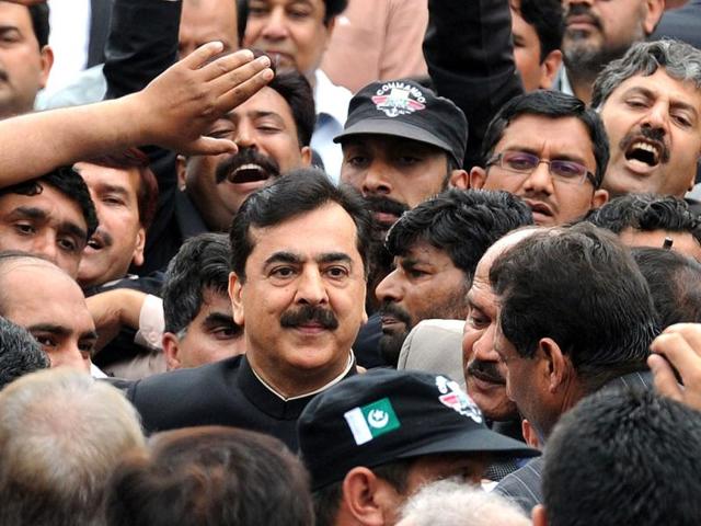 Pak PM Yousuf Raza Gilani is surrounded by security and supporters as he leaves the Supreme Court after a verdict in Islamabad. AFP Photo/Aamir Qureshi