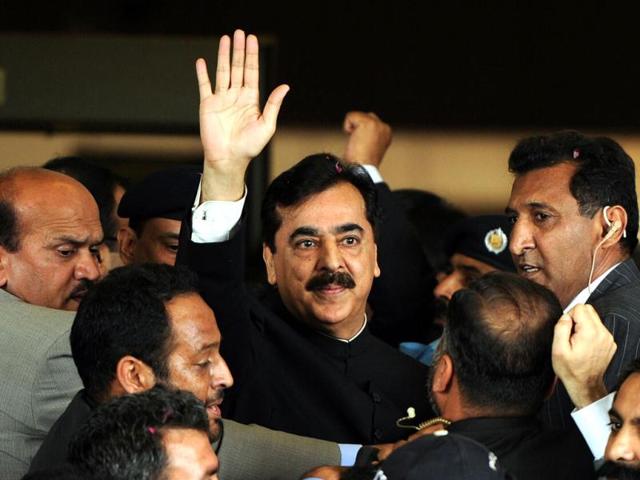 Pak PM Yousuf Raza Gilani is escorted by security as he waves upon his arrival at the Supreme Court building in Islamabad. AFP Photo/Aamir Qureshi