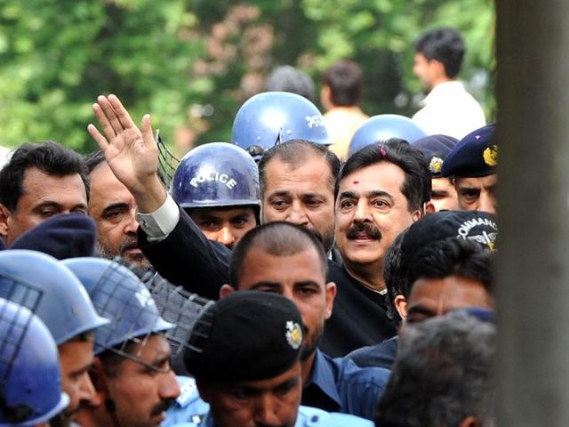 Pak PM Yousuf Raza Gilani is escorted by security as he waves upon his arrival at the Supreme Court building in Islamabad. Gilani was convicted of contempt of court by the country's highest court but avoided a jail term. AFP Photo/Aamir Qureshi