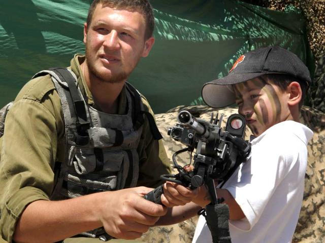 An Israeli boy plays with a rifle during a traditional military weapon display to mark the 64th anniversary of Israel's Independence at the West Bank settlement of Efrat on April 26, 2012 near the biblical city of Bethlehem. AFP/Gali Tibbon