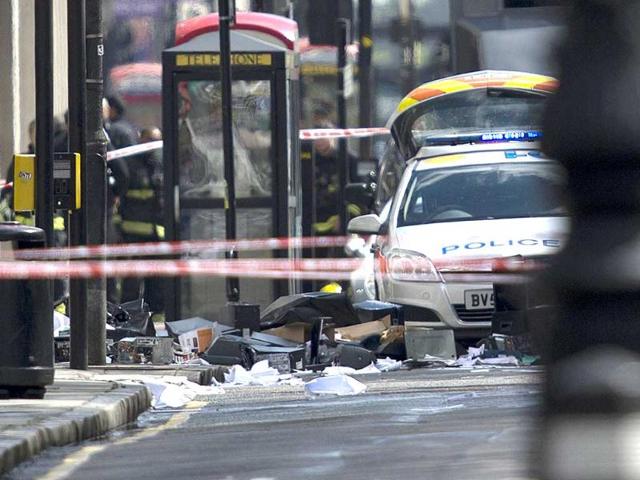 Debris litters the pavement and road in front of police vehicles below an office building were according to reports an armed man was causing a disturbance in central London. AFP Photo/Ben Stansall