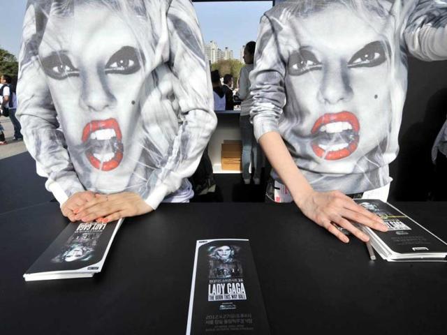 South Korean staff wear t-shirts showing the face of Lady Gaga at an information desk ahead of a concert outside Seoul's Olympic Stadium. AFP/Jung Yeon-je