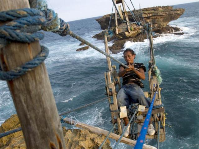 Fisherman Siswanto rides on a self-built wooden cable car, created by himself, to cross the sea at Timang beach in Gunung Kidul, near the ancient city of Yogyakarta. Reuters/Dwi Oblo