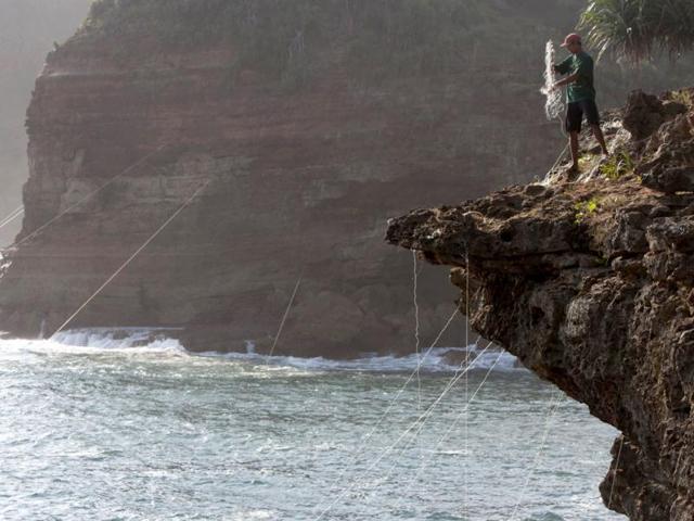 A fisherman fixes nets on rocks to catch lobsters at Timang beach in Gunung Kidul, near the ancient city of Yogyakarta. Reuters/Dwi Oblo