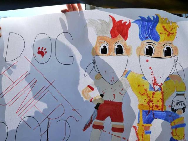 A Ukrainian animal-rights activist holds a poster depicting Euro 2012 mascots Slavek and Slavko signed 'Dog hunters' during a rally in front of the cabinet of the ministers building in Kiev. AFP/Sergei Supinsky