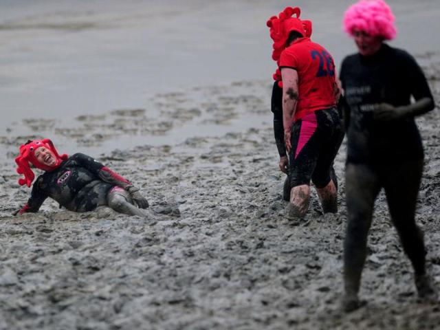 A competitor falls and laughs in the mud as she takes part in the Maldon Mud Race in Essex. AFP/Carl Court