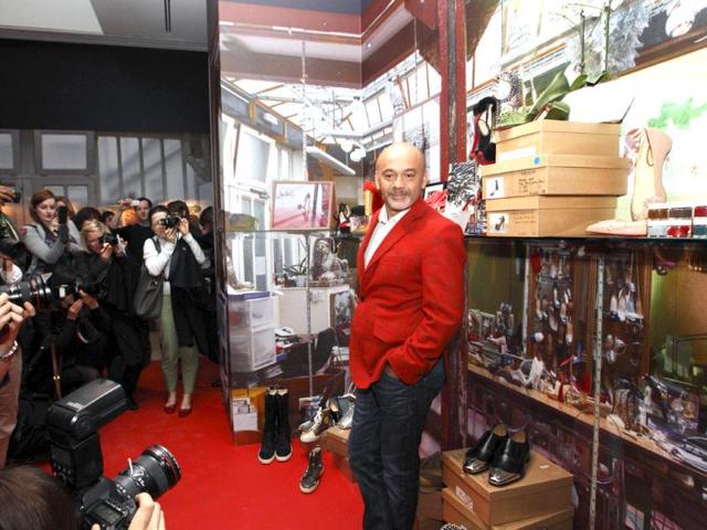 French shoe designer Christian Louboutin poses for a picture in front of his work during a preview of an exhibition showcasing 20 years of the famous red-soled shoes at the Design Museum in London. AFP Photo/Justin Tallis