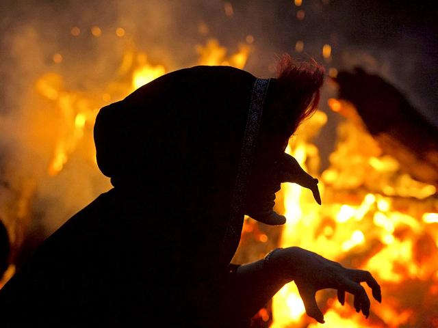A woman dressed as a witch dances in front of a fire during the Walpurgis Night at the famous Hexentanzplatz (Witches' dance ground)' in the Harz mountains near Thale, northern Germany. (AP Photo/Jens Meyer)