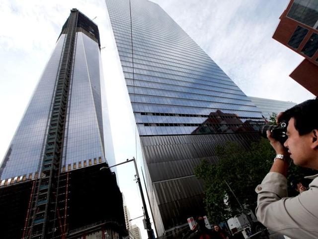 A man takes a photo as construction continues on One World Trade Center (L) after workers moved a steel column into place to make it New York City's tallest building in New York City. (Mario Tama/Getty Images/AFP)