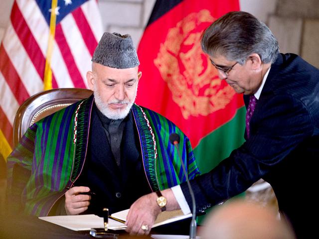 Afghan President Hamid Karzai signs the US-Afghanistan strategic partnership agreement on May 2, 2012 at the Presidential Palace in Kabul, Afghanistan. The agreement provides US military and financial support to Afghanistan for 10 years after the 2014 scheduled troop withdraw. AFP/Mandel Ngan