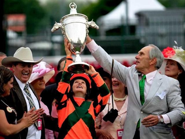 Rosie Napravnik celebrates with the trophy after riding atop Believe You Can to win the 138th running of the Kentucky Oaks as owner Brereton Jones (R) and trainer Larry Jones (L) look on at Churchill Downs in Louisville, Kentucky. Rob Carr/Getty Images/AFP