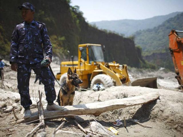A member of the rescue team from Nepal police with his sniffer dog, named Rescue, looks on at the site that used to be a small village, swiped away by a flash flood caused by an avalanche in the Annapurna mountain range on Saturday, in Kaski district. At least 19 people, including three foreigners, are confirmed to have died and 45 still missing till today due to the flood in Pokhara and adjoining villages in Kaski district, according to a local media report. (Reuters)