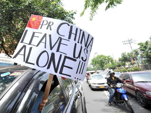 A motorist displays a anti-China placard in front of the Chinese consulate in the financial district of Manila ahead of a protest. AFP Photo/Ted Aljibe
