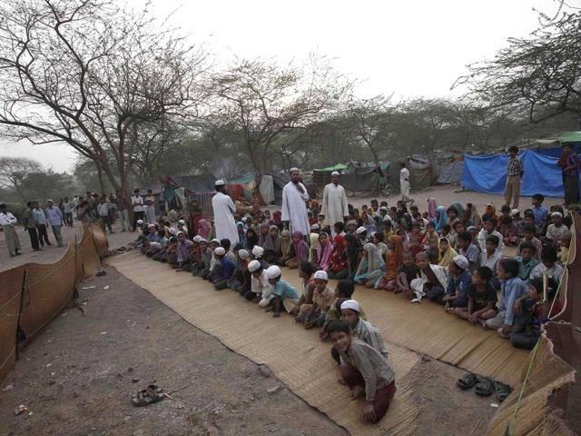 People, who say they belong to the Burmese Rohingya community from Myanmar, sit in an open air madrasa, or a religious school, at a camp in New Delhi. REUTERS/Adnan Abidi