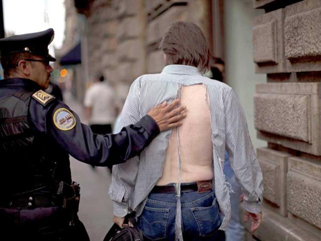 A police officer escorts a man who participated in a street fight that took place in downtown Mexico City. AP/Alexandre Meneghini