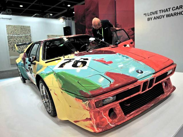 A man cleans the windshield of a car painted by Andy Warhol at Asia's premier art fair 'Art HK' in Hong Kong. AFP PHOTO / Philippe Lopez