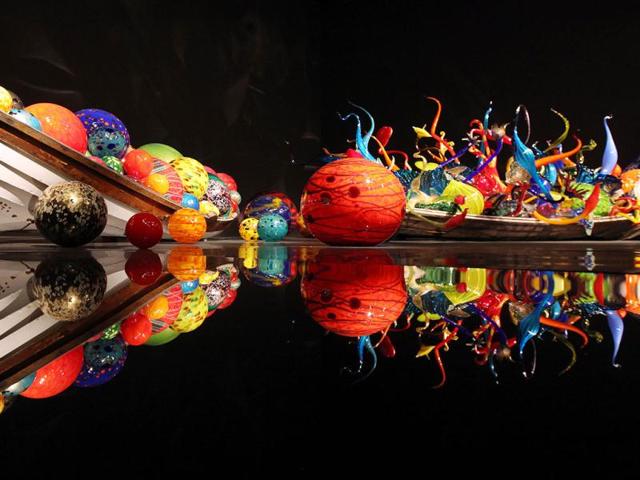 The "Ikebana and Float Boat" is seen on display and in reflection during a preview of the Chihuly Garden and Glass exhibit at the Seattle Center in Seattle. The new, permanent 1.5 acre exhibit is located near the base of the Space Needle and opens to the public Monday, May 21. It looks at the career of artist Dale Chihuly and features an eight-gallery exhibition hall, conservatory and garden as well as a cafe with a selection of Chihuly's collections of vintage accordions, radios, clocks and other mid-century memorabilia. (AP Photo/Elaine Thompson)