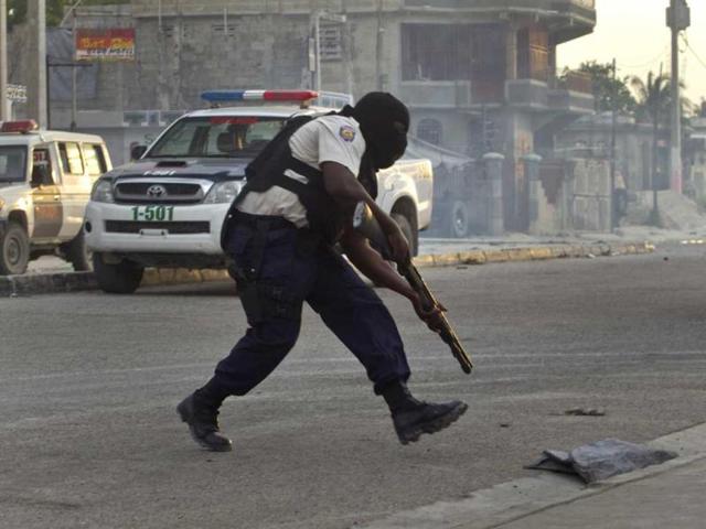 A national police officer runs toward a former army base to take a position during clashes between police and members of the dissolved army in Port-au-Prince, Haiti. AP Photo/Ramon Espinosa