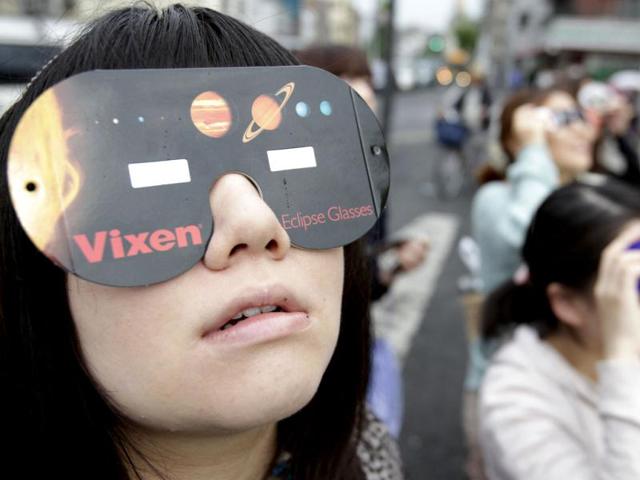 People watch the annular solar eclipse in Fujisawa, near Tokyo. The annular eclipse, in which the moon passes in front of the sun leaving only a golden ring around its edges, was visible to wide areas across the continent. AP Photo/Shizuo Kambayashi