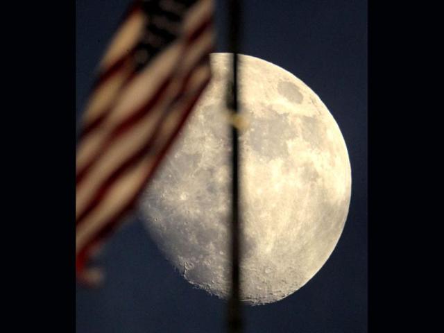 An American flag atop city hall waves in the wind against the backdrop of a waxing moon in Kansas City, Mo. AP/Charlie Riedel