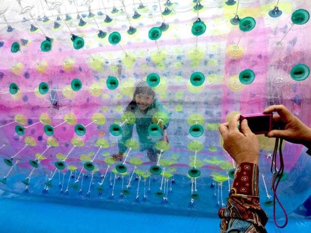 A woman takes a picture of her granddaughter playing inside a balloon float on water at the Chaoyang park during International Children's Day in Beijing. AP/Andy Wong