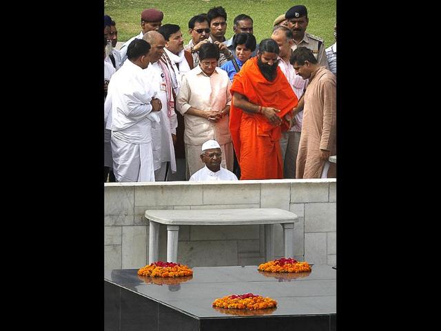 Anna Hazare and yoga guru Baba Ramdev offer tributes at the Mahatma Gandhi memorial, along with supporters, before starting their day-long fast, in New Delhi. AP/Manish Swarup