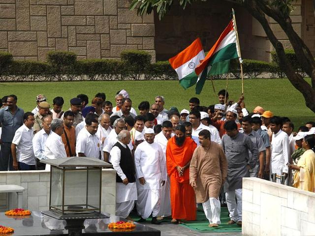 Anna Hazare (in a white cap at center) with Baba Ramdev (in an orange robe) and supporters, offers tributes at the Mahatma Gandhi memorial before stating their day-long fast in New Delhi. AP/Manish Swarup