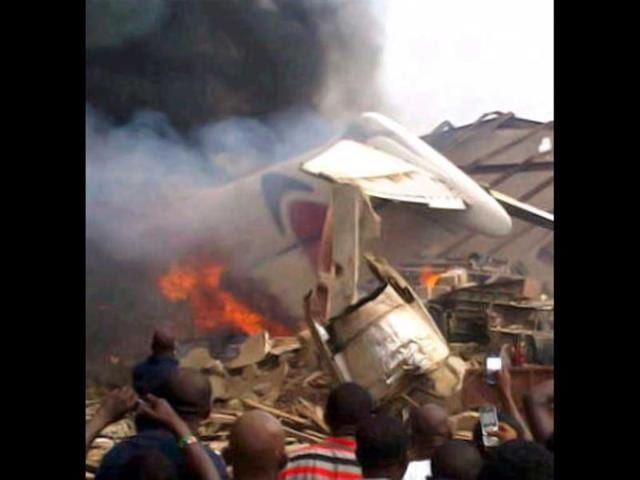 A picture taken with a photo camera shows residents of the Iju district of Lagos gathering at the site where a Dana company aircraft crashed into a two-storey building on June 3, 2012 in Lagos. AFP PHOTO / CKN