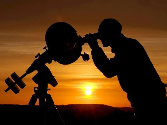A hobby astronomer points his telescope at the yellow disk of the rising Sun as he observes the transit of planet Venus in Ziegenhain near Jena, eastern Germany. AFP/Angelika Warmuth