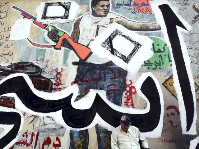 An Egyptian man sits in front of a wall sprayed graffiti at Tahrir Square in Cairo. Reuters/Amr Abdallah Dalsh, File
