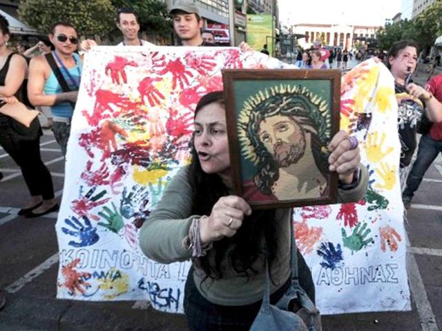 A Christian woman displays a holy icon in central Athens during the gay pride parade. Some 1000 people took part at a march organised by Greece's gay and lesbian community, with the main slogan ' love me, its for free' . AFP Photo/ Louisa Gouliamaki