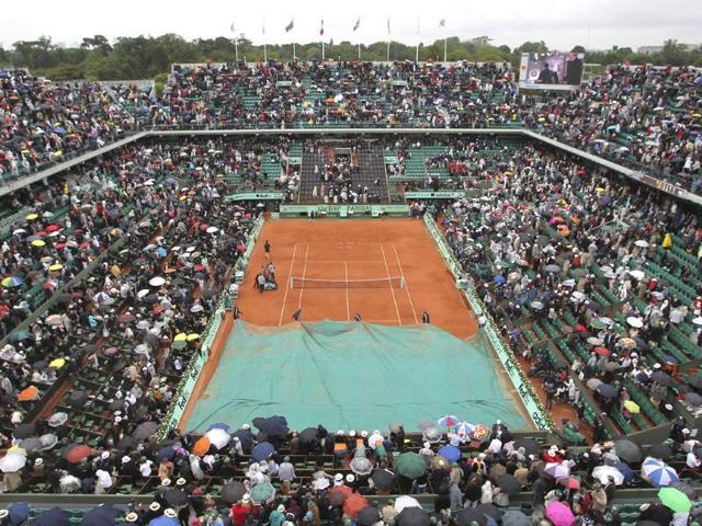 Stadium employees cover center court as the mens final match between Rafael Nadal of Spain and Novak Djokovic of Serbia was suspended because of the rain at the French Open tennis tournament in Roland Garros stadium in Paris, (AP Photo/David Vincent)