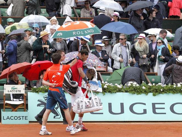 Rafael Nadal of Spain leaves the court under an umbrella as rain stops the play during his men's singles final match against Novak Djokovic of Serbia at the French Open tennis tournament at the Roland Garros stadium in Paris Reuters/Gonzalo Fuentes