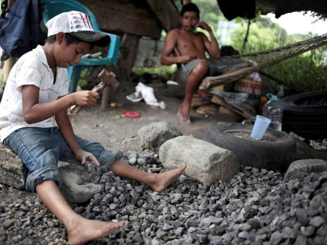 Josue Alexander Chavez (L), 9 years old, uses a hammer to break stones as he works near the road to Mazatenango, about 165 km (102 miles) north of Guatemala City, ahead of World Day Against Child Labour. Chavez works with his parents, breaking stones for the construction of houses. He works from 7am-5pm and makes 20 quetzales ($2.50) per day. Reuters/Jorge Dan Lopez
